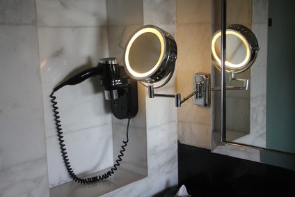 A hotel bathroom with a mirror, fan and a magnifying glass
